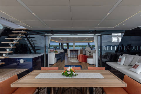 A modern and stylish interior space with a wooden table, comfortable seating, and large windows offering a scenic view of the outdoors.