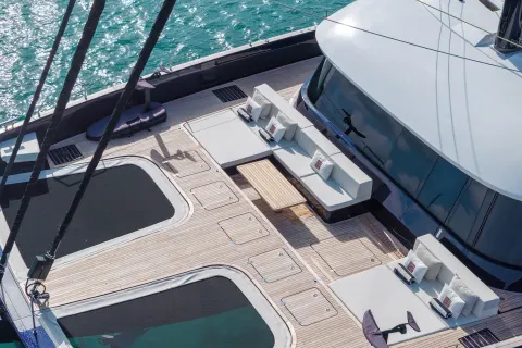 A modern yacht with a spacious deck and seating areas, surrounded by the vibrant turquoise waters of the ocean.