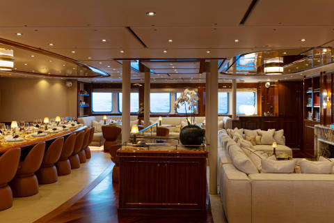 A luxurious and spacious interior with a long dining table, comfortable seating, and large windows providing a scenic view.