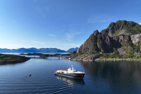 A serene fjord surrounded by majestic mountains, with a small boat sailing peacefully on the calm waters.