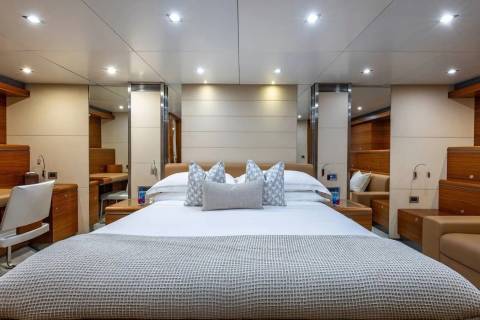 A luxurious bedroom with a large bed in the foreground and mirrored walls reflecting more of the room in the background.