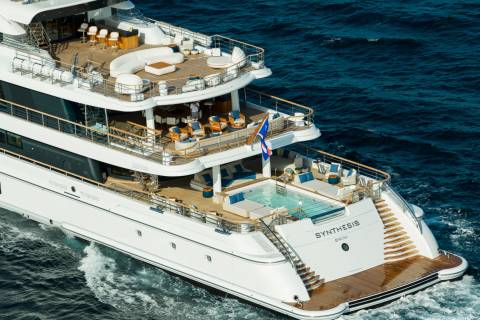 A luxurious yacht with a swimming pool and lounge areas on its decks cruises through the deep blue ocean.