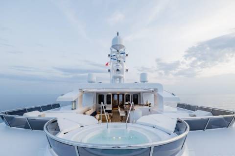 A luxurious yacht with a jacuzzi in the foreground is at sea under a cloudy sky.