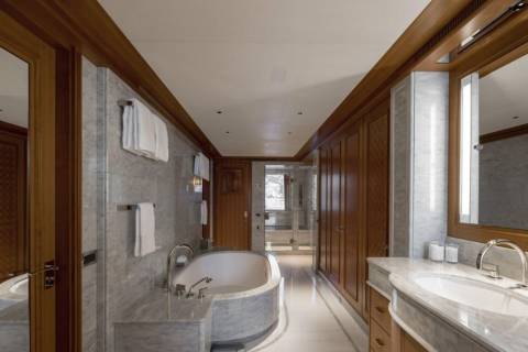 A luxurious bathroom with a freestanding tub in the foreground and wooden cabinetry and a vanity in the background.