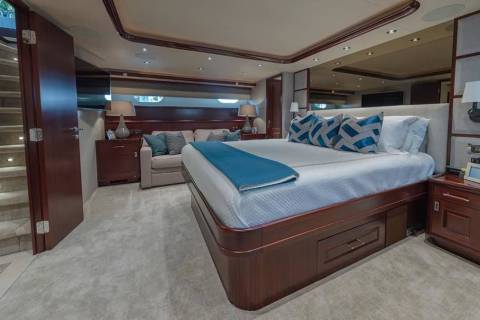 A luxurious bedroom with a large bed and blue accents occupies the foreground, while a seating area and a staircase are visible in the background.