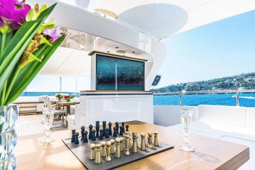 A luxurious yacht deck offers a stunning view of the Mediterranean coast with a chess game and champagne ready for play.