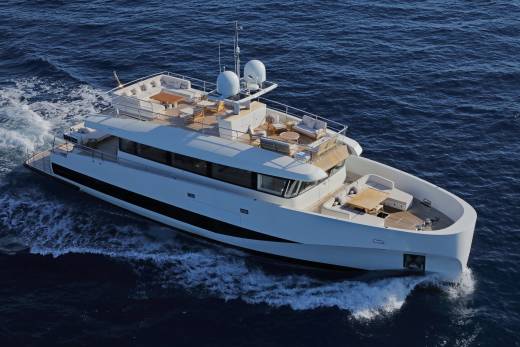 A sleek white yacht glides through the deep blue ocean, leaving a trail of white foam in its wake.