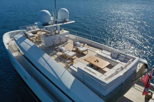 Luxurious outdoor seating and a bar area beckon guests to relax on this elegant yacht's sun-drenched deck.
