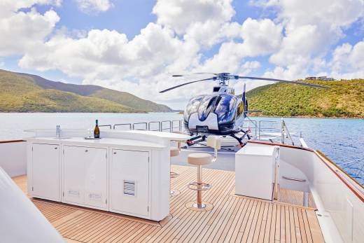 A sleek helicopter rests on the deck of a luxurious yacht, ready for island hopping in a tropical paradise.