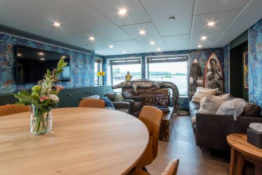A luxurious lounge with vibrant jungle-themed wallpaper and a stunning waterfront view creates an exotic ambiance.