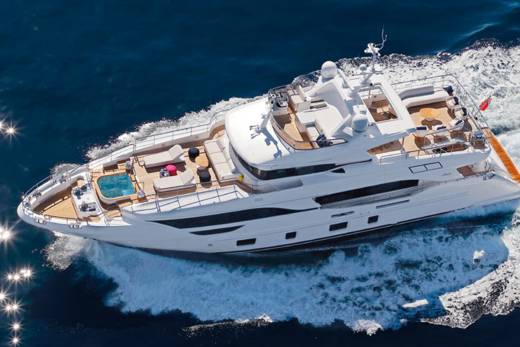 A luxurious white yacht glides through the deep blue ocean, leaving a trail of white foam in its wake.