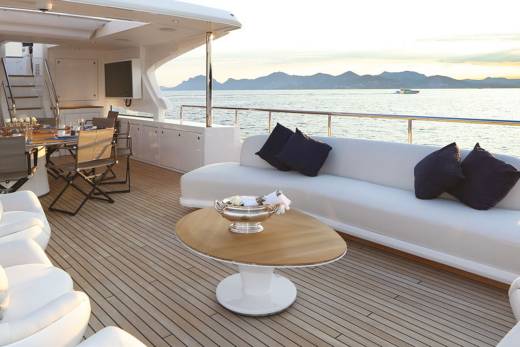Relax on the spacious deck of a luxury yacht as the sun sets over the tranquil sea.