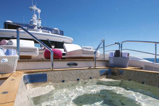 A luxurious yacht features a steaming hot tub on its deck, perfect for relaxing with a view of the ocean.