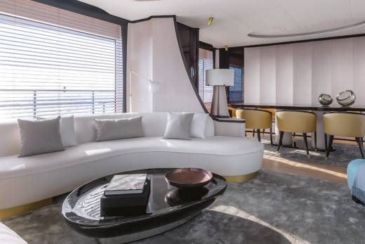 A modern yacht lounge offers a serene escape with its plush white sofa, sleek coffee table, and elegant dining area.