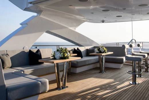 Luxurious outdoor seating and tables on a yacht deck offer a serene spot to enjoy the ocean breeze.