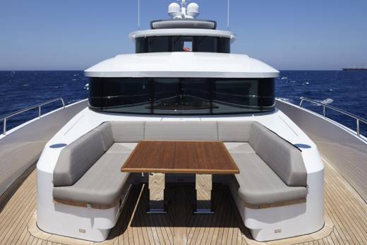 A modern yacht with plush seating and a wooden table offers a luxurious spot for al fresco dining on the open sea.