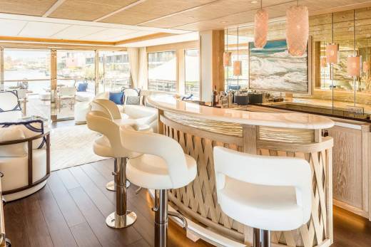Luxurious bar stools and a sleek counter invite guests to enjoy drinks with a view of the tranquil waterway.