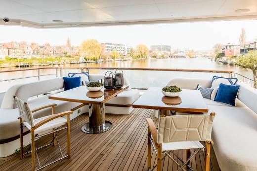 Relax on the deck of this luxurious yacht, enjoying the serene waterside view and comfortable seating.