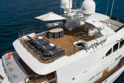 Luxurious sun loungers and a dining set await guests on the expansive deck of the yacht Elena.
