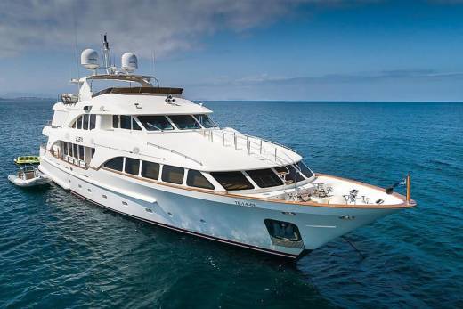 A luxurious white yacht glides serenely on the deep blue ocean under a partly cloudy sky.