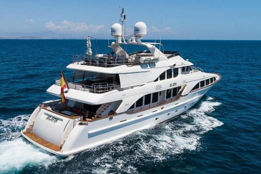 A luxurious white yacht cruises through the sparkling blue ocean under a clear sky.