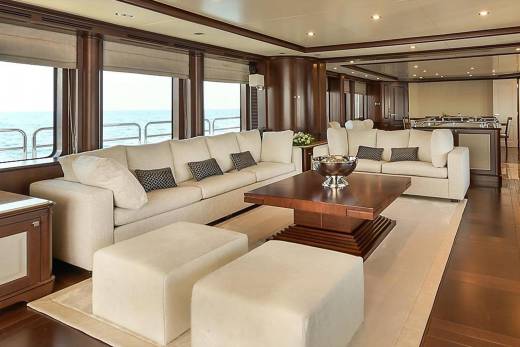 Luxurious cream sofas and a dark wood coffee table create a sophisticated lounge area overlooking the ocean.