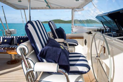 Striped cushions and a polished helm await a leisurely cruise on the turquoise waters of a tropical paradise.