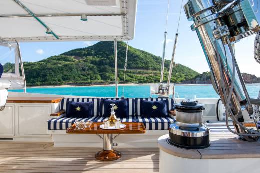 Relax on the deck of a luxurious yacht with a refreshing drink and a view of a tropical island.