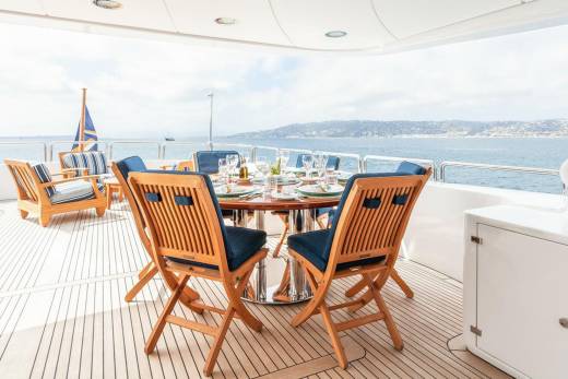 Dine al fresco on the deck of a luxury yacht overlooking a picturesque coastline.