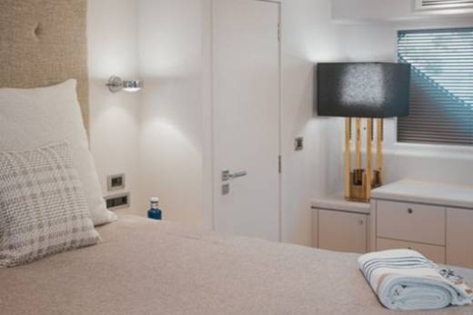 A modern bedroom features a plush bed, a stylish lamp, and a window with blinds.