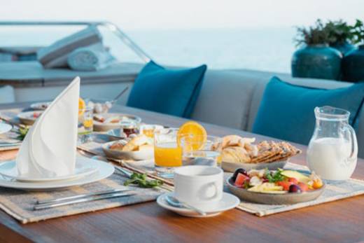 Enjoy a delightful breakfast spread on a yacht deck with the ocean as your backdrop.