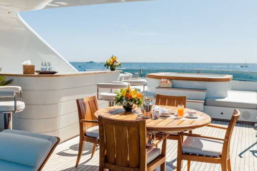 A sun-drenched yacht deck offers a perfect setting for a leisurely breakfast overlooking the sparkling blue ocean.