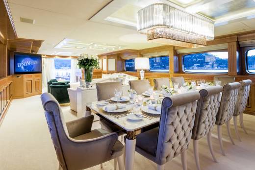 Luxurious dining chairs surround a marble-topped table set for a formal meal aboard a lavish yacht.