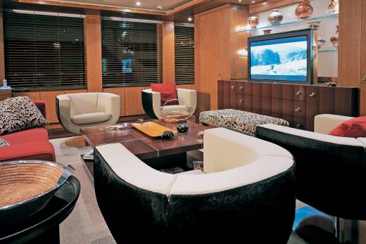 Luxurious yacht interiors feature plush seating, a large television, and elegant wooden cabinetry.