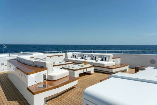 Luxurious white sofas and sleek wooden accents create an inviting outdoor lounge space on this elegant yacht.