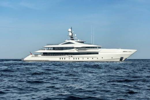 The luxurious superyacht LUSINE glides through the deep blue ocean under a clear sky.