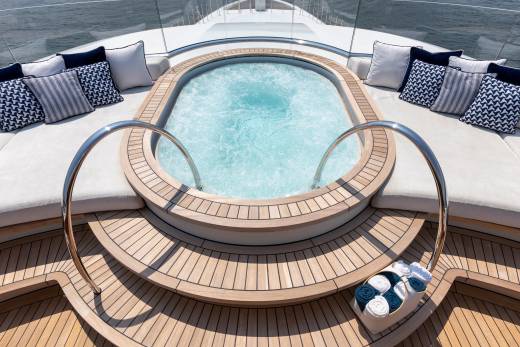 Relax in the bubbling turquoise waters of this luxurious yacht's built-in hot tub, surrounded by plush cushions and polished chrome railings.