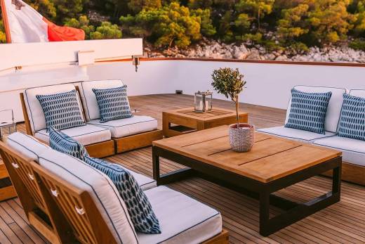 Relax on the spacious deck of a luxury yacht, surrounded by lush greenery and the gentle sea breeze.