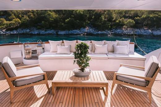 Relax on the deck of a luxurious yacht surrounded by the stunning turquoise waters and lush green coastline.
