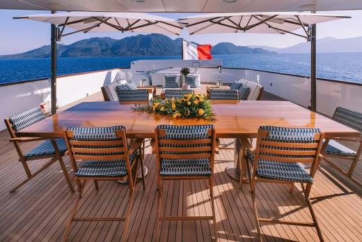 Dine al fresco on the deck of a luxury yacht surrounded by stunning ocean views and picturesque mountains.