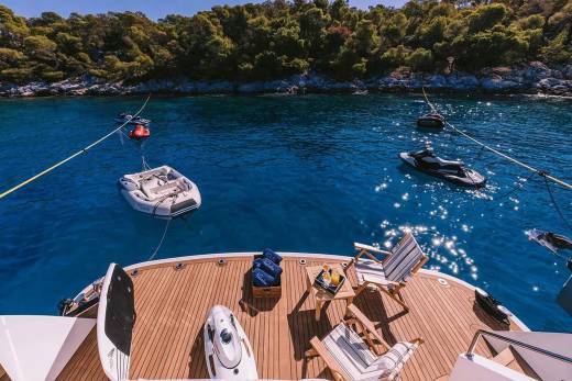 Relax on the deck of a luxury yacht surrounded by crystal-clear blue waters and lush green hills.