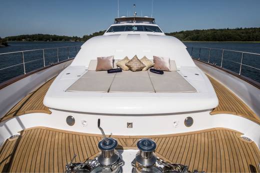 Luxurious yacht deck with plush cushions and polished winches offers a serene escape on the tranquil blue waters.