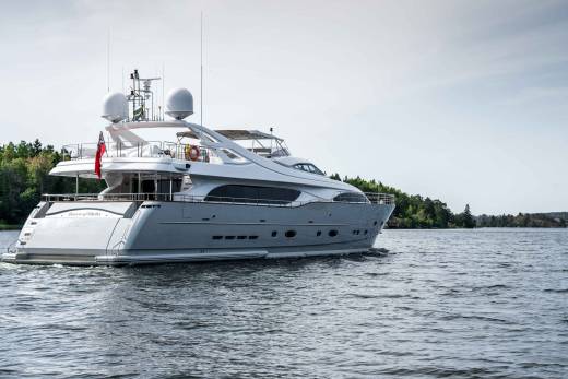 The luxurious yacht "Queen of Sheba" glides through calm waters near a tree-lined shore.