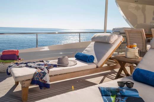 Relax on the deck of a luxury yacht with plush loungers, colorful towels, and the endless blue ocean stretching out before you.