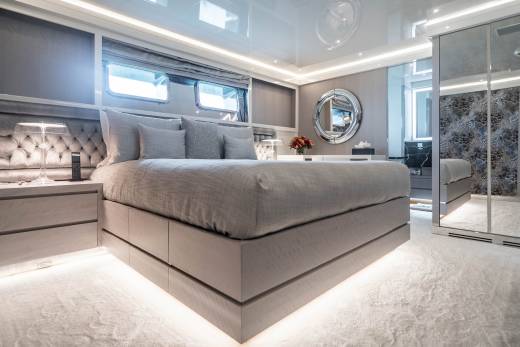 Luxurious yacht master suite features a plush king-sized bed, elegant mirrored closet, and ambient under-bed lighting.