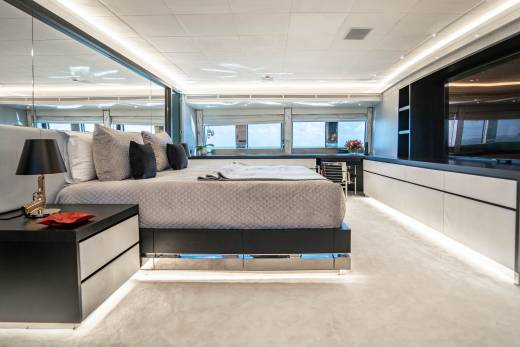Luxurious yacht bedroom features a plush bed, mirrored walls, and a stunning ocean view through panoramic windows.