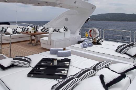Luxurious yacht deck seating with a backgammon board and drinks invites relaxation on the open water.