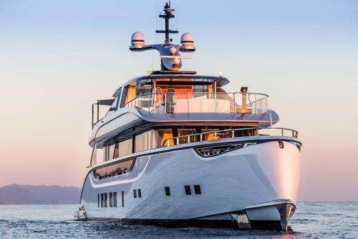 A sleek, modern yacht glides across calm waters under a soft, pastel sky at sunrise.