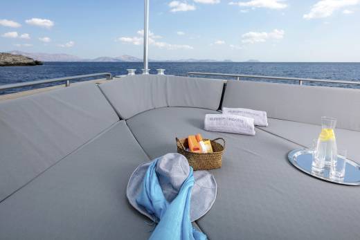 Relax on the plush deck of a yacht with refreshing drinks and sun essentials while cruising the azure sea.