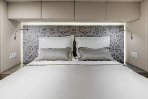 A modern bedroom features a plush bed with a patterned headboard and integrated lighting, creating a serene ambiance.